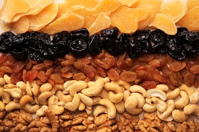 Mix of delicious dried nuts and fruits on beige background, flat lay