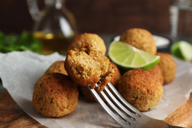 Photo of Delicious falafel balls with lime on wooden board, closeup