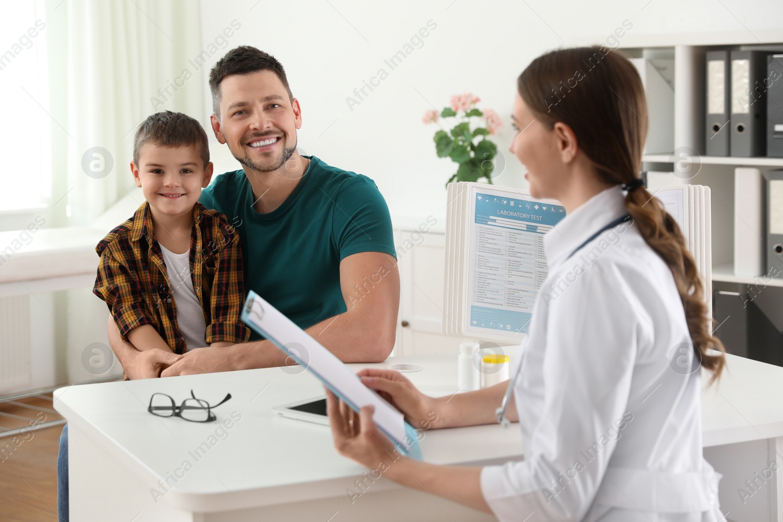 Photo of Father and son visiting pediatrician. Doctor working with little patient in hospital