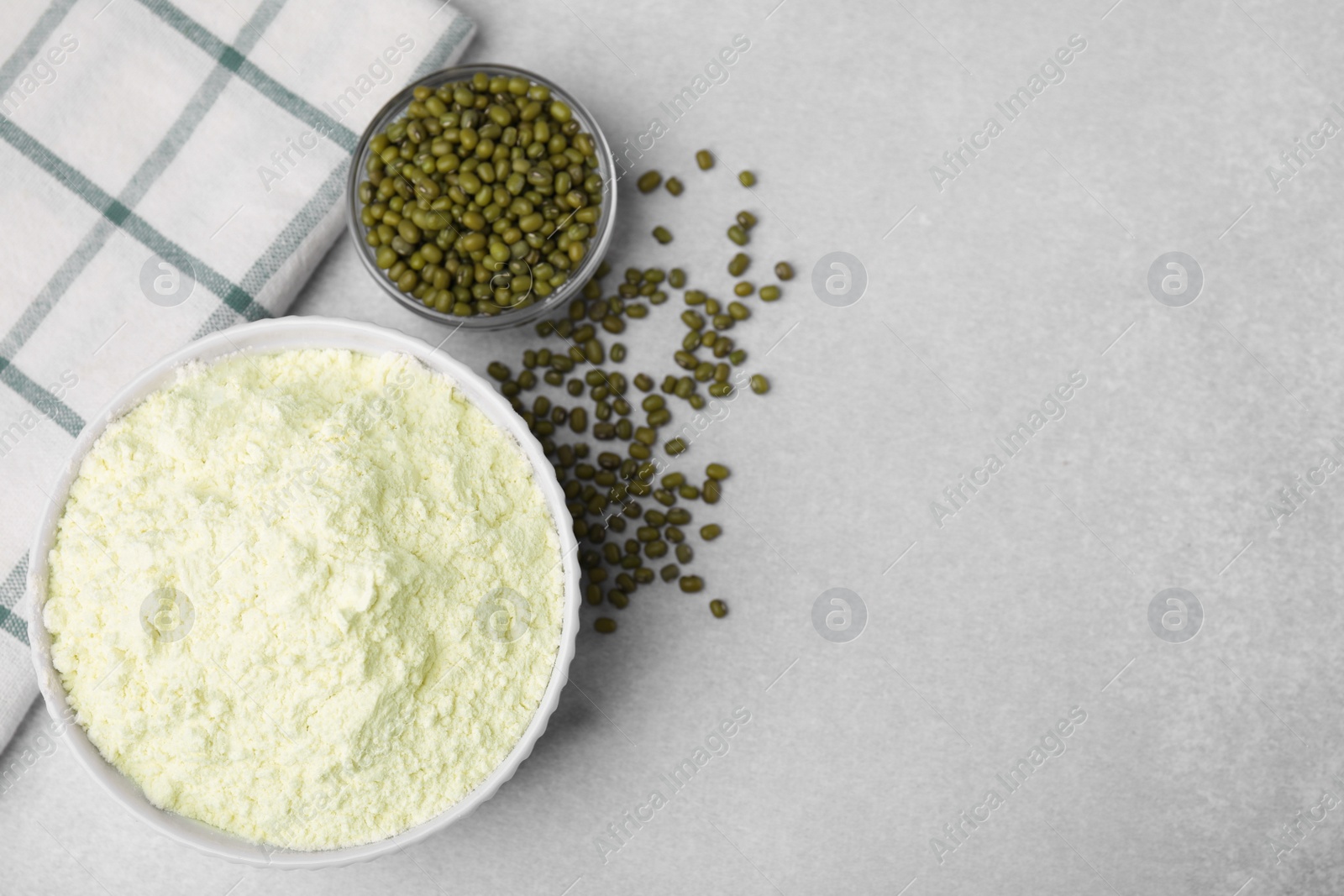 Photo of Mung bean flour in bowl and seeds on white table, flat lay. Space for text