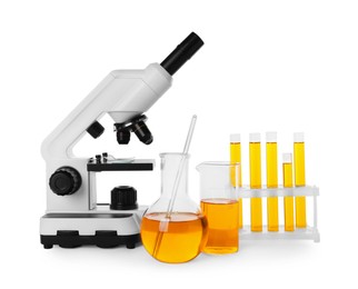 Laboratory glassware with orange liquid and microscope isolated on white