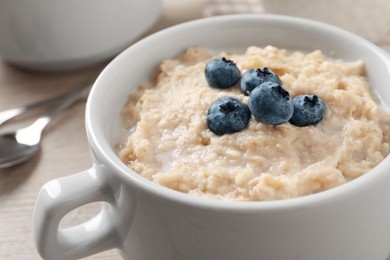 Photo of Tasty oatmeal porridge with blueberries in bowl on table, closeup