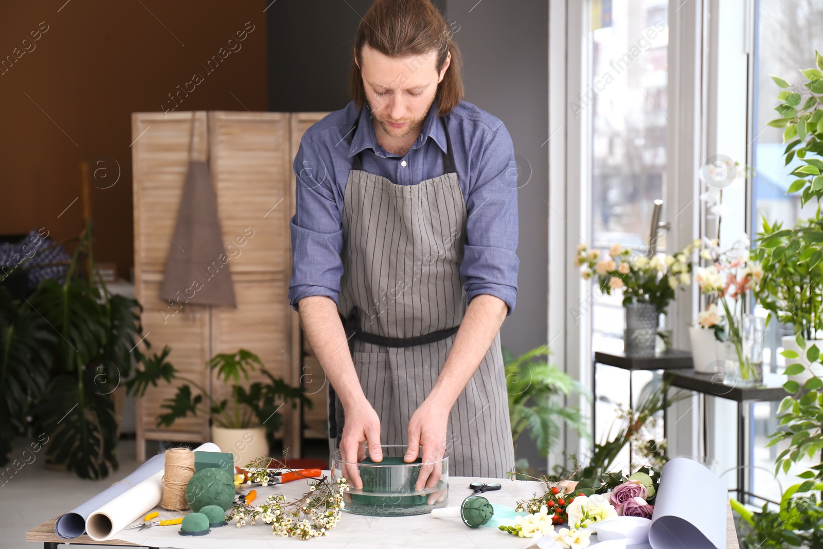 Photo of Male florist creating floral composition at workplace