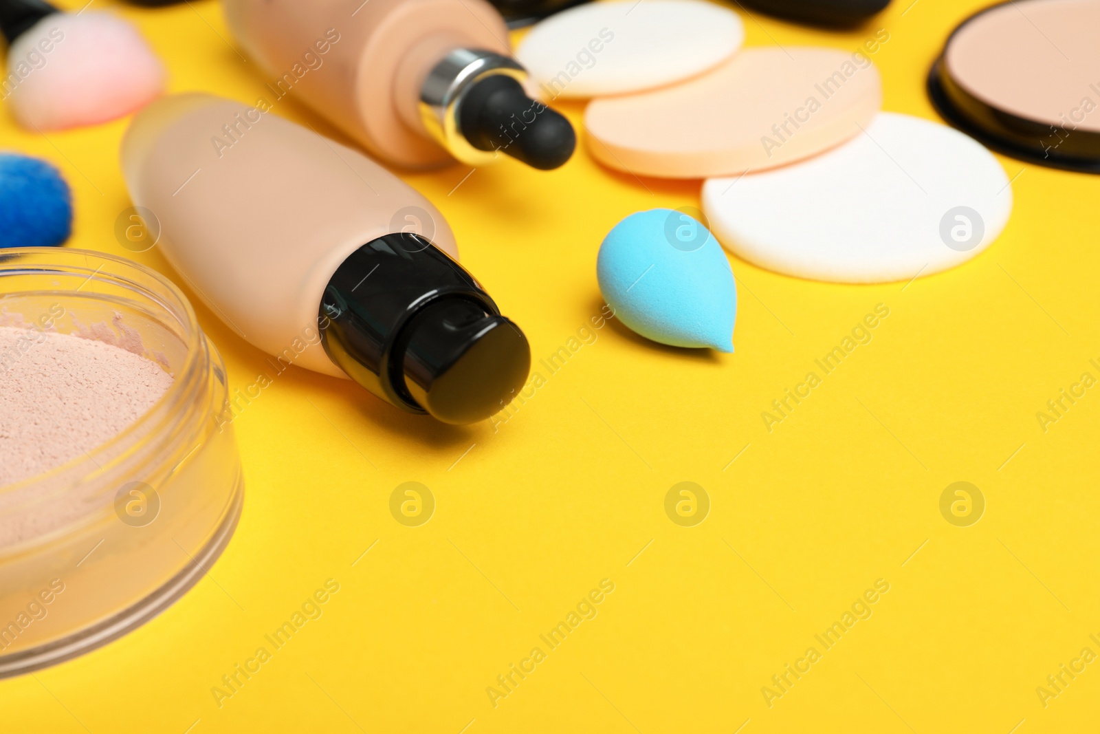 Photo of Composition with skin foundation, powder and beauty accessories on color background