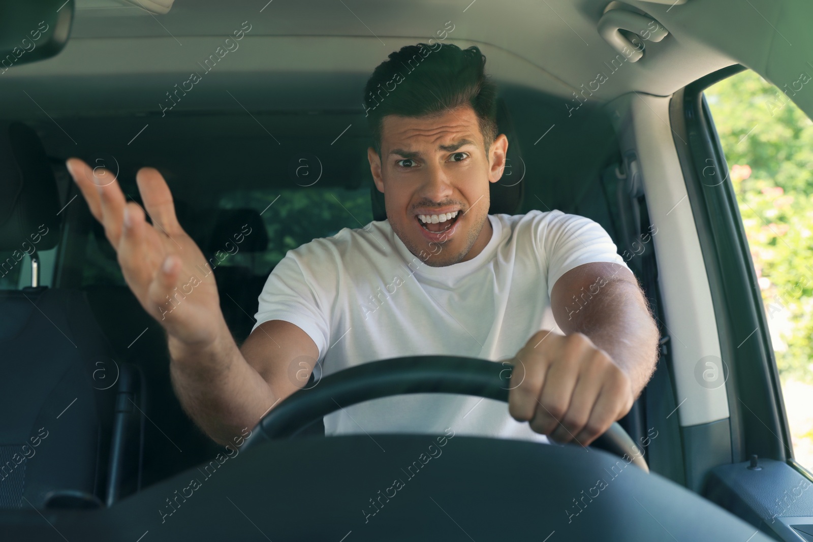 Photo of Stressed angry man in driver's seat of modern car, view through windshield