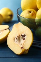 Photo of Tasty ripe quinces in bowl on blue wooden table, closeup