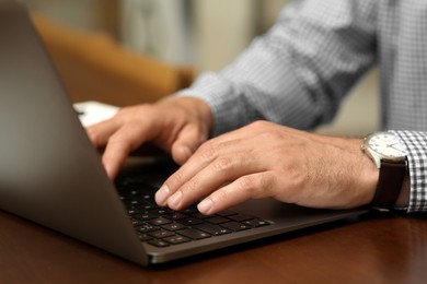 Man working on laptop at table in cafe, closeup