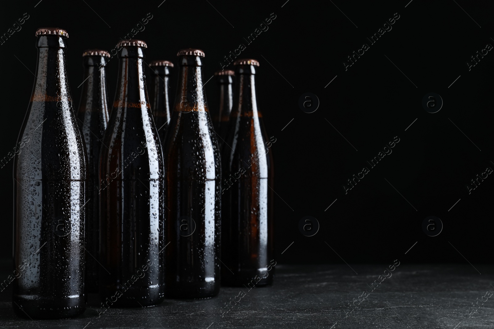 Photo of Bottles of beer on table against black background. Space for text