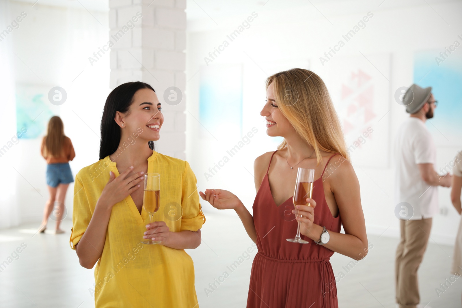 Photo of Young women with glasses of champagne at exhibition in art gallery