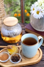 Photo of Tray with delicious tea and ingredients on wooden table