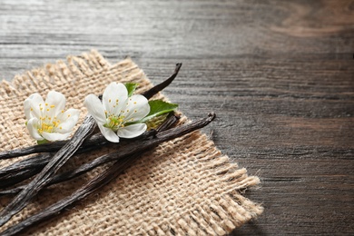 Photo of Vanilla sticks and flowers on wooden background