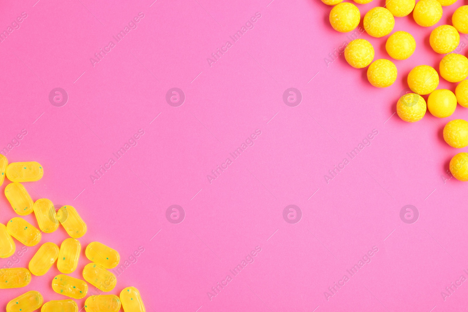 Photo of Many different lemon drops on pink background, flat lay. Space for text