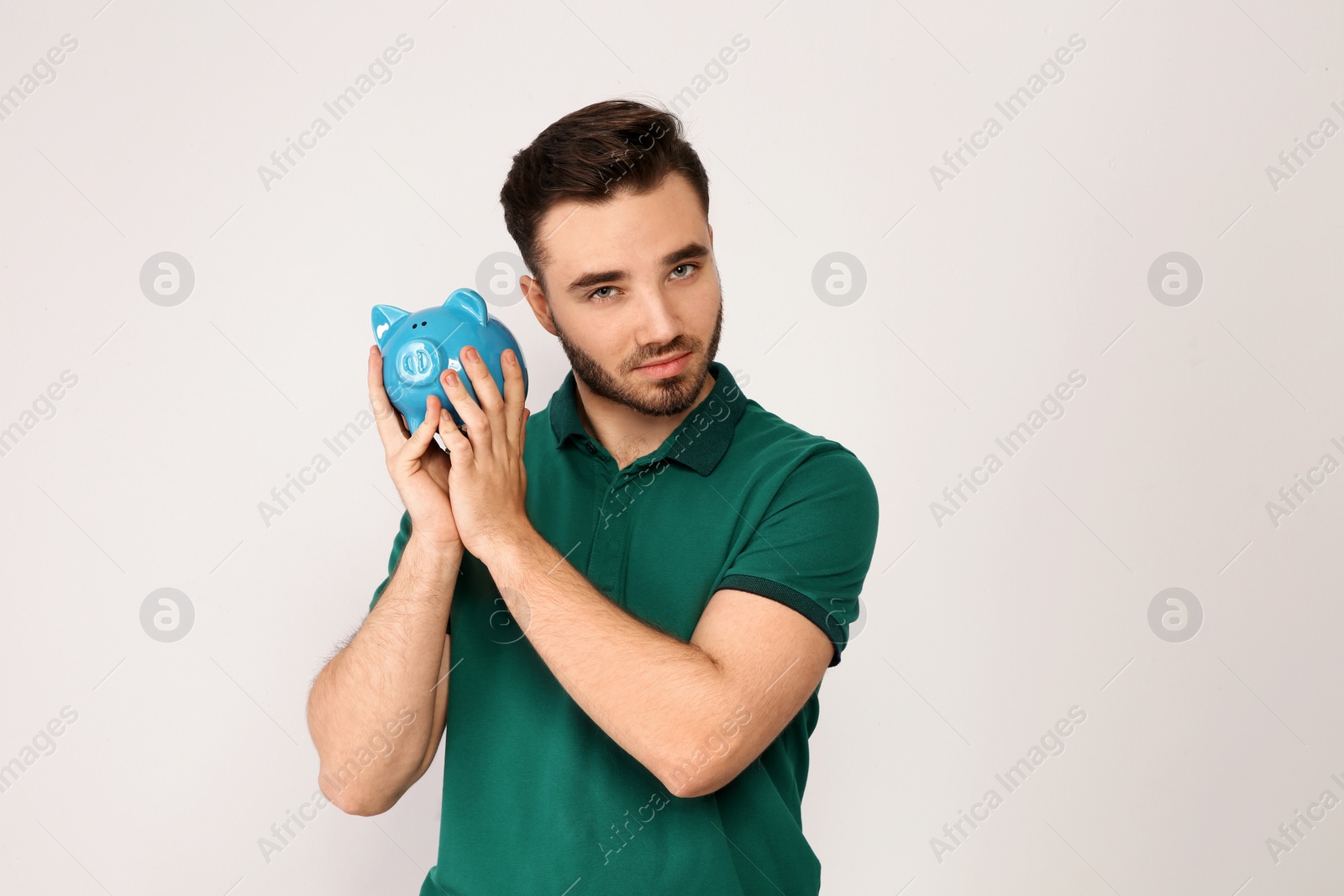 Photo of Young man with piggy bank on light background