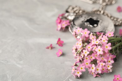 Photo of Beautiful Forget-me-not flowers and pocket watch on grey table, closeup. Space for text