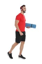 Handsome man with yoga mat and headphones on white background