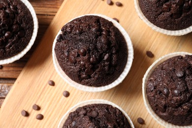 Tasty chocolate muffins on wooden table, flat lay