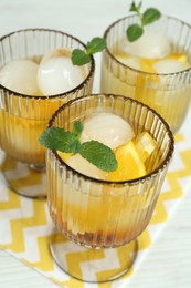 Photo of Delicious cocktails with orange, mint and ice balls on white table, closeup