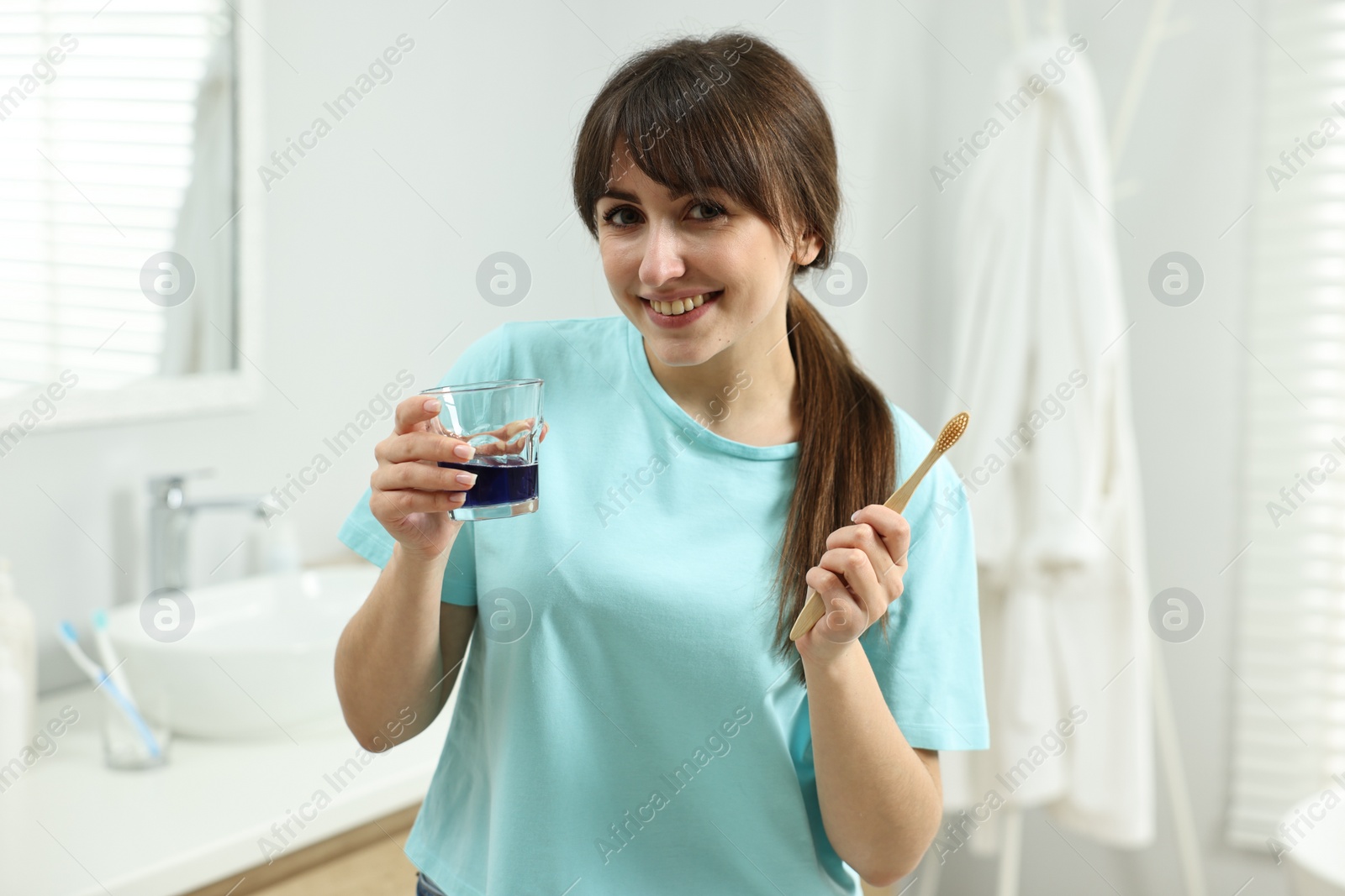 Photo of Young woman with mouthwash and toothbrush in bathroom