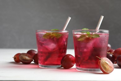 Photo of Delicious grape soda water and berries on white table. Refreshing drink