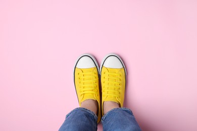 Photo of Woman in stylish gumshoes on pink background, top view