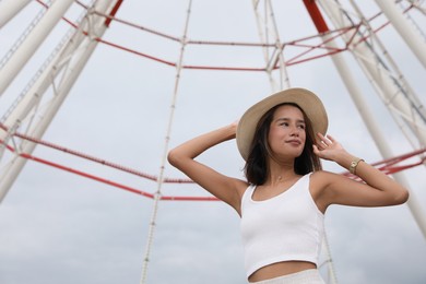 Photo of Beautiful young woman near Ferris wheel outdoors, low angle view
