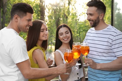 Friends clinking glasses of Aperol spritz cocktails at outdoor cafe