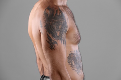 Tattooed man on grey background, closeup view