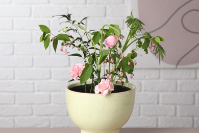 Beautiful ikebana for stylish house decor. Floral composition with fresh flowers and branches near white brick wall