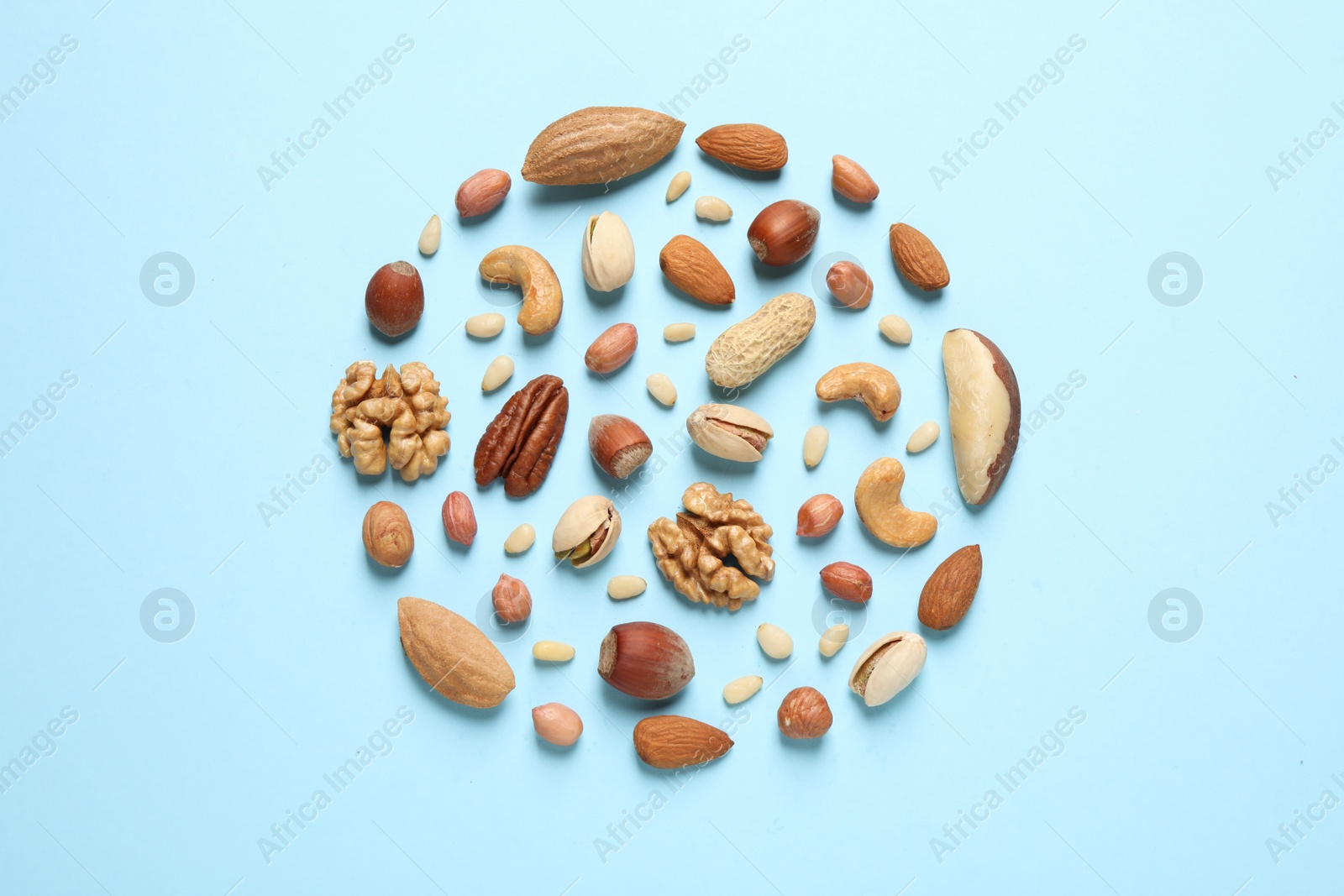 Photo of Different delicious nuts on light blue background, flat lay