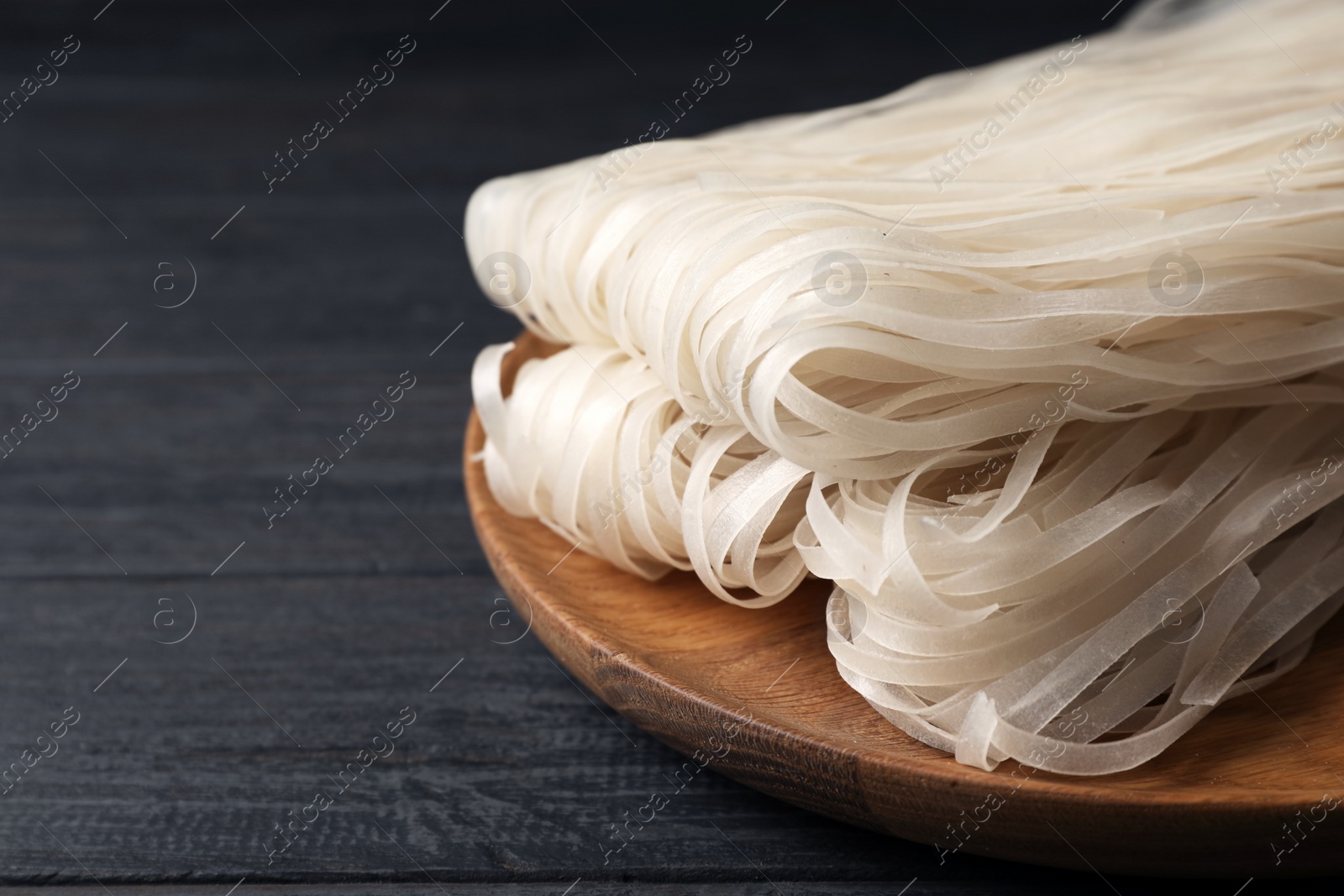 Photo of Plate with raw rice noodles on wooden table. Space for text