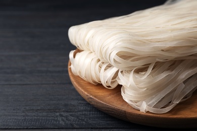 Plate with raw rice noodles on wooden table. Space for text