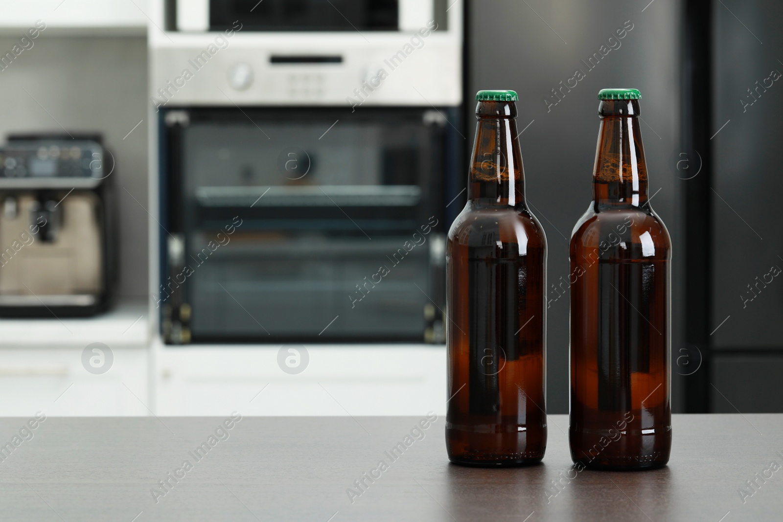 Photo of Bottles of beer on grey table in kitchen. Space for text