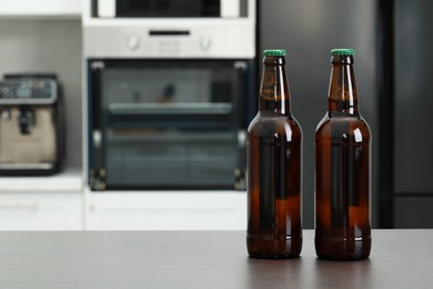 Bottles of beer on grey table in kitchen. Space for text