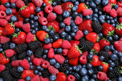 Mix of different ripe tasty berries as background, top view