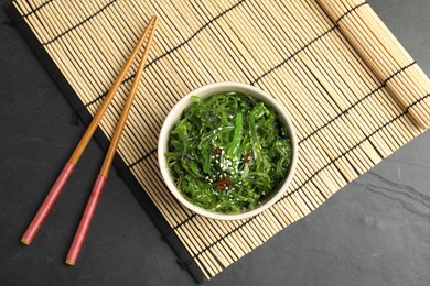 Japanese seaweed salad served on black table, flat lay