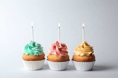Photo of Delicious birthday cupcakes with candles on gray background