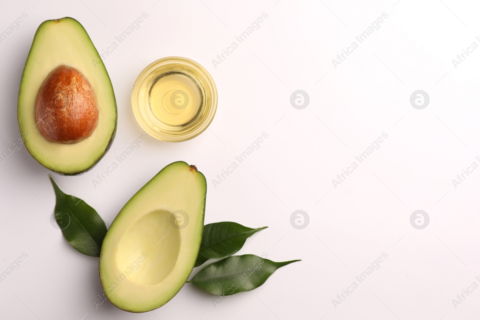 Photo of Cooking oil in bowl and fresh avocados on white background, flat lay. Space for text