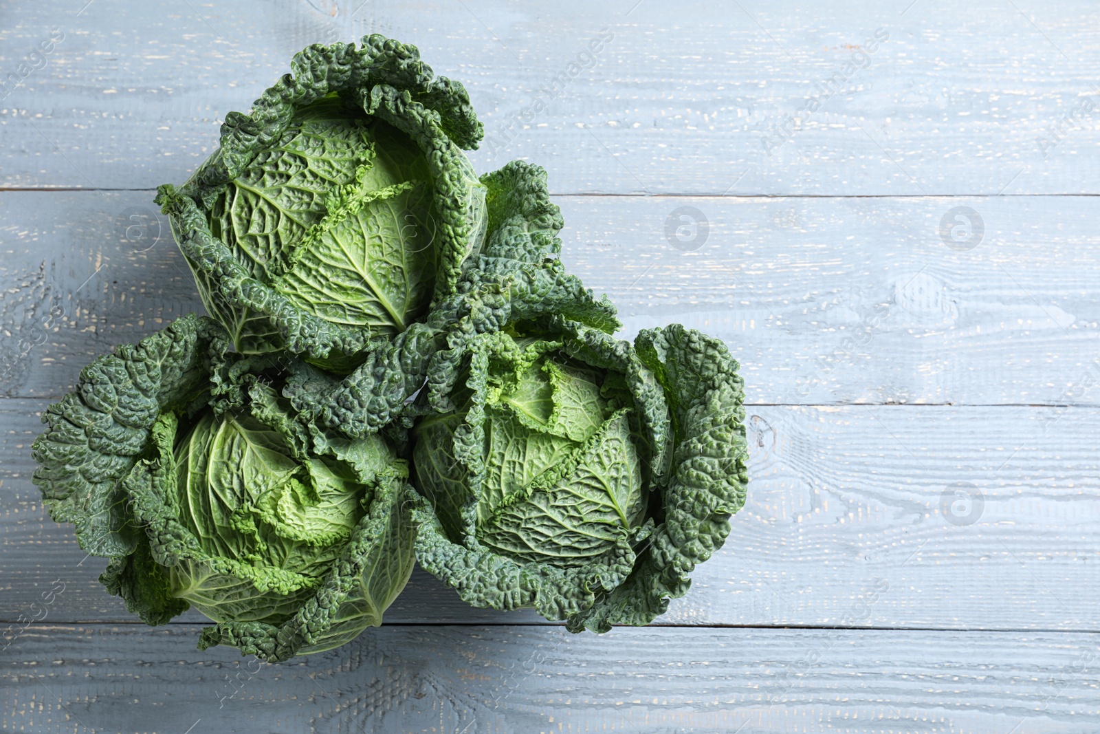 Photo of Fresh green savoy cabbages on grey wooden table, flat lay. Space for text