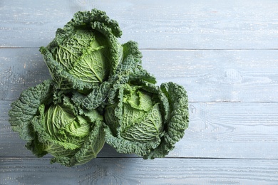 Photo of Fresh green savoy cabbages on grey wooden table, flat lay. Space for text