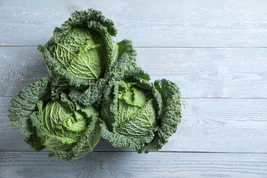 Fresh green savoy cabbages on grey wooden table, flat lay. Space for text