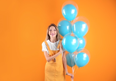 Photo of Young woman with air balloons on color background