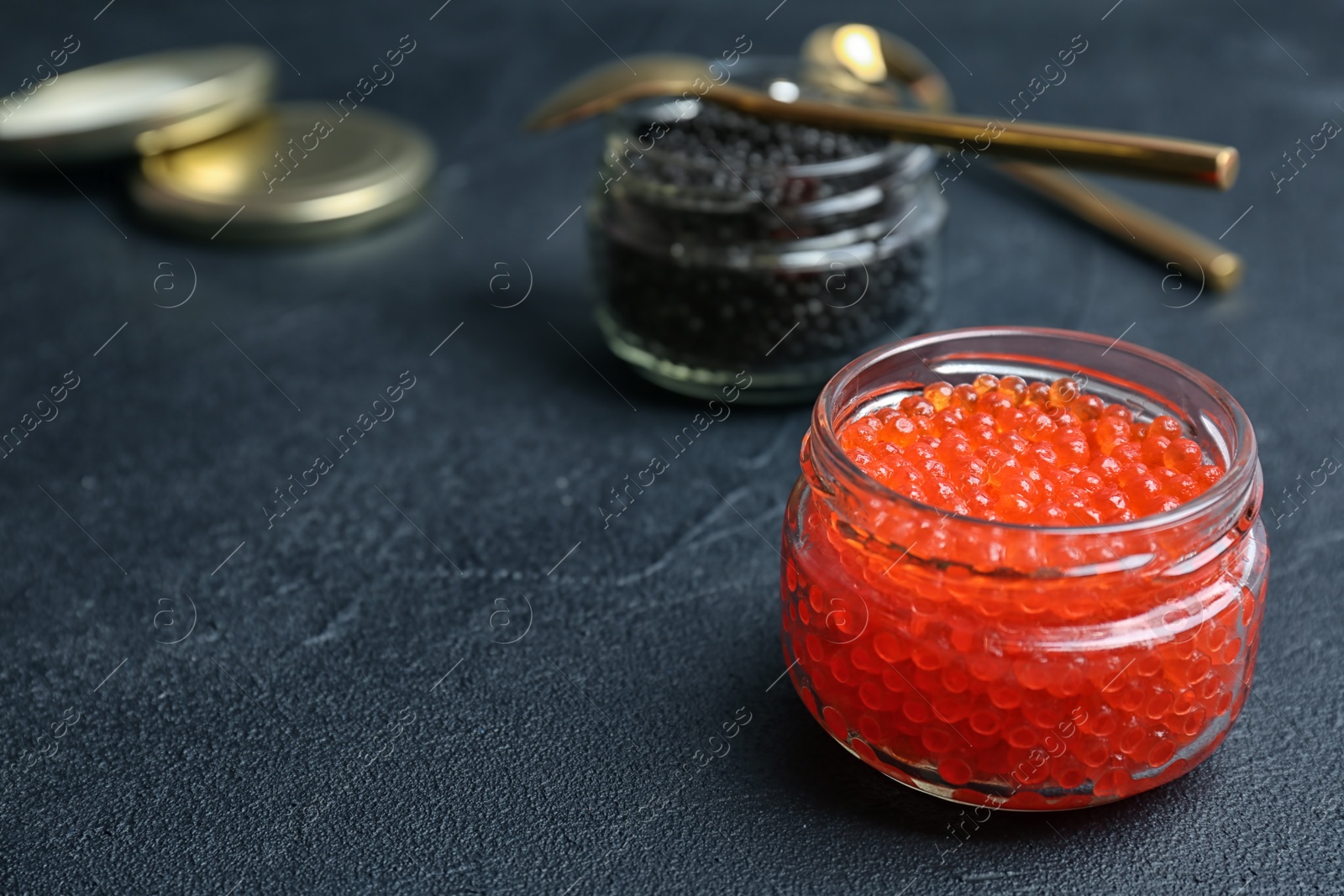 Photo of Glass jars with black and red caviar on table