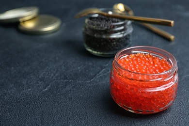 Glass jars with black and red caviar on table