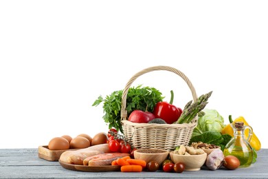 Healthy food. Basket with different fresh products on grey wooden table against white background