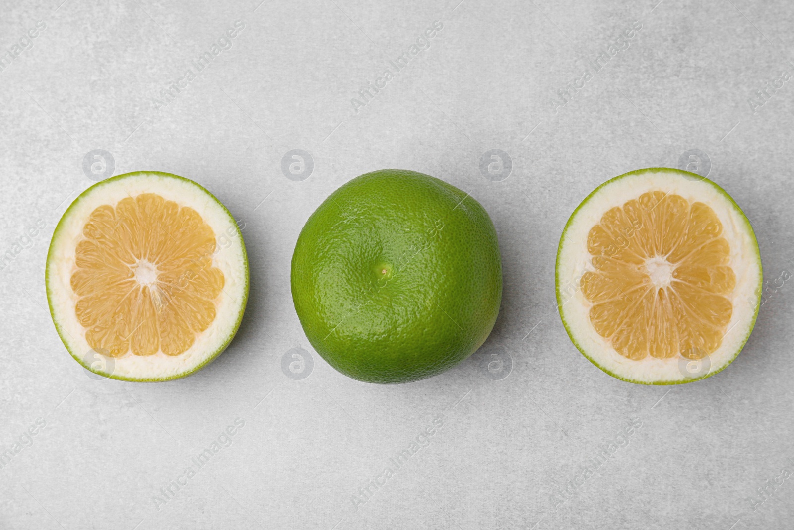 Photo of Whole and cut sweetie fruits on light table, flat lay