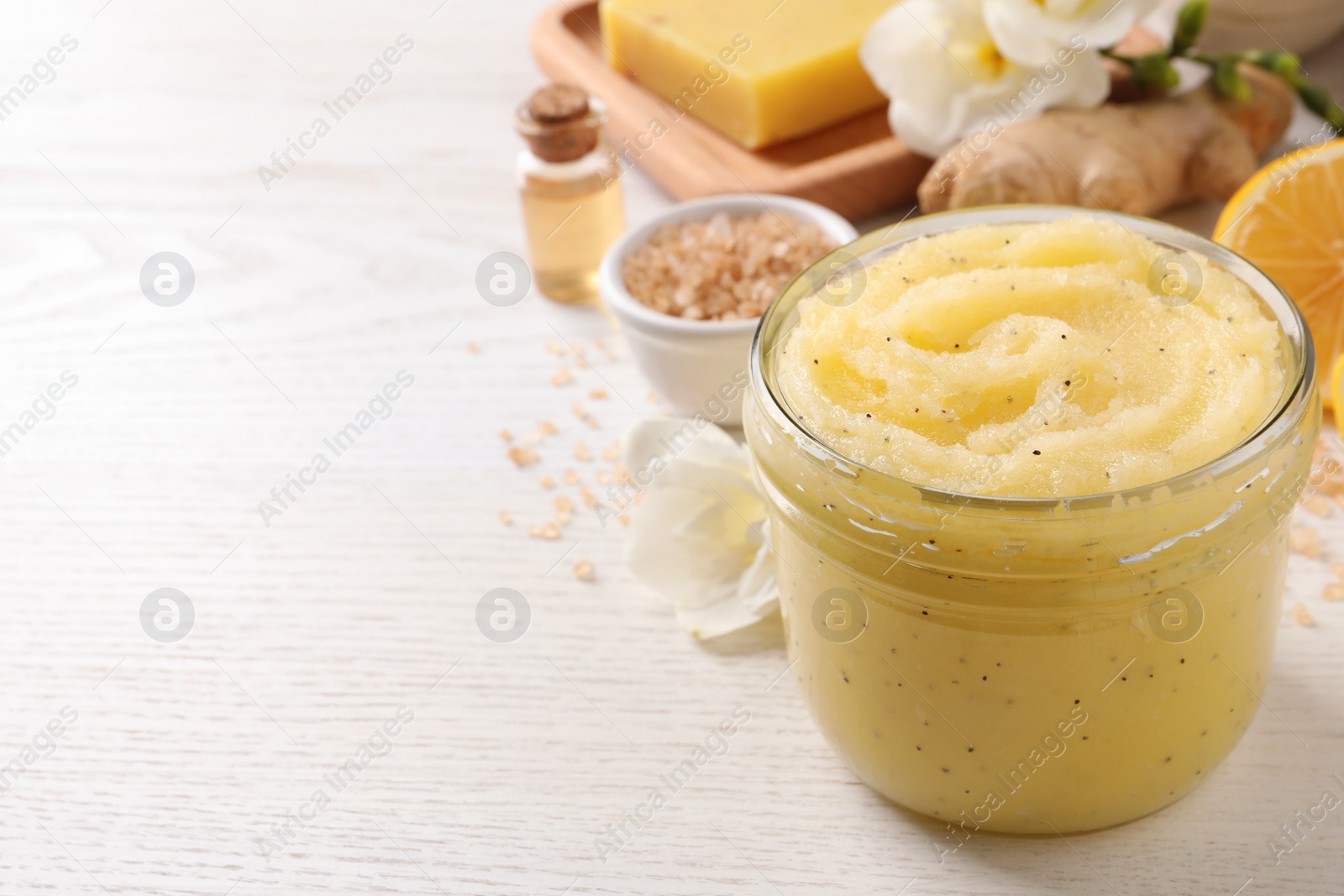 Photo of Body scrub in glass jar on white wooden table, closeup. Space for text
