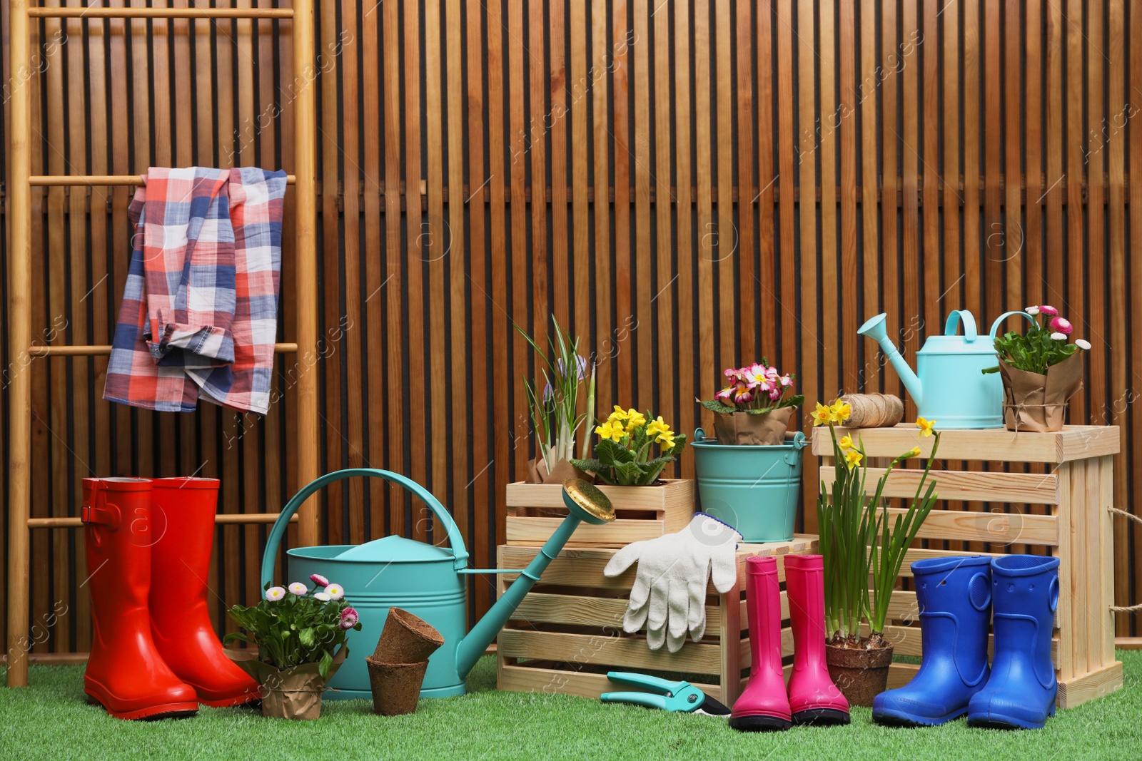 Photo of Composition with different gardening tools on artificial grass at wooden wall. Space for text