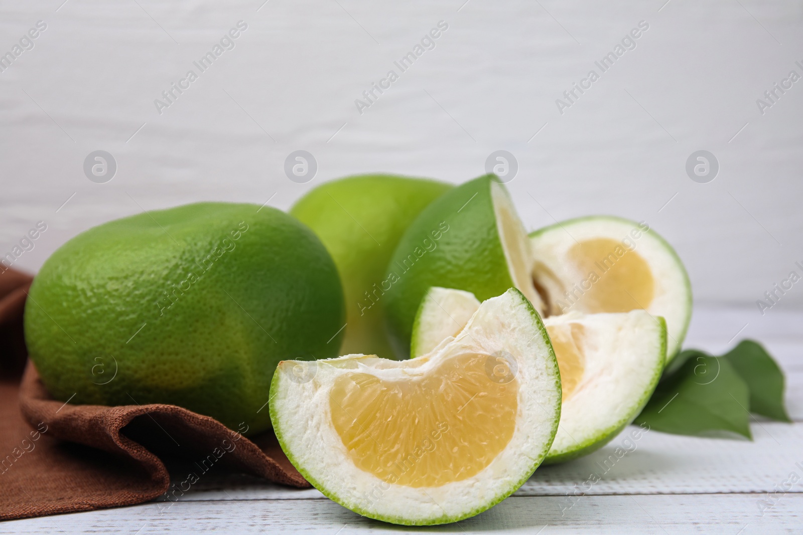 Photo of Whole and cut sweetie fruits on white wooden table, closeup