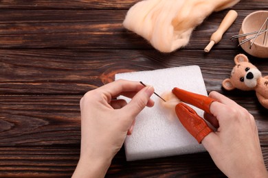 Photo of Woman felting from wool at wooden table, closeup. Space for text