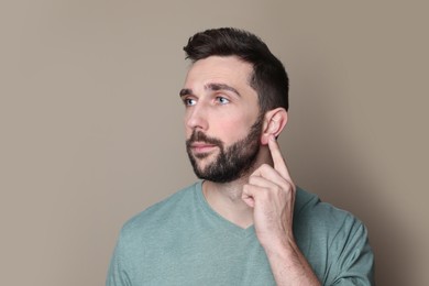 Photo of Man pointing at his ear on grey background